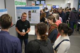 Ein HSD-Mitarbeiter spricht mit Besucherinnen und Besuchern vor einem wissenschaftlichen Poster zur computergestützten Erkennung und Klassifizierung von Düngemitteln.